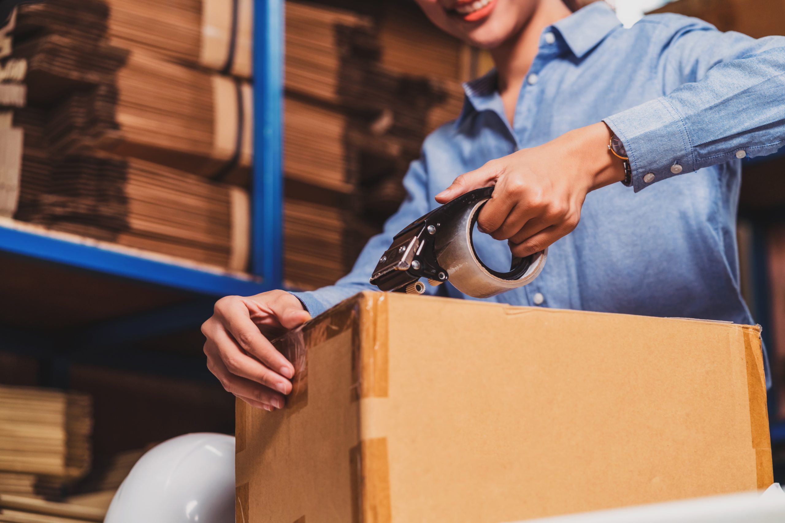 Warehouse worker sealing a cardboard parcel